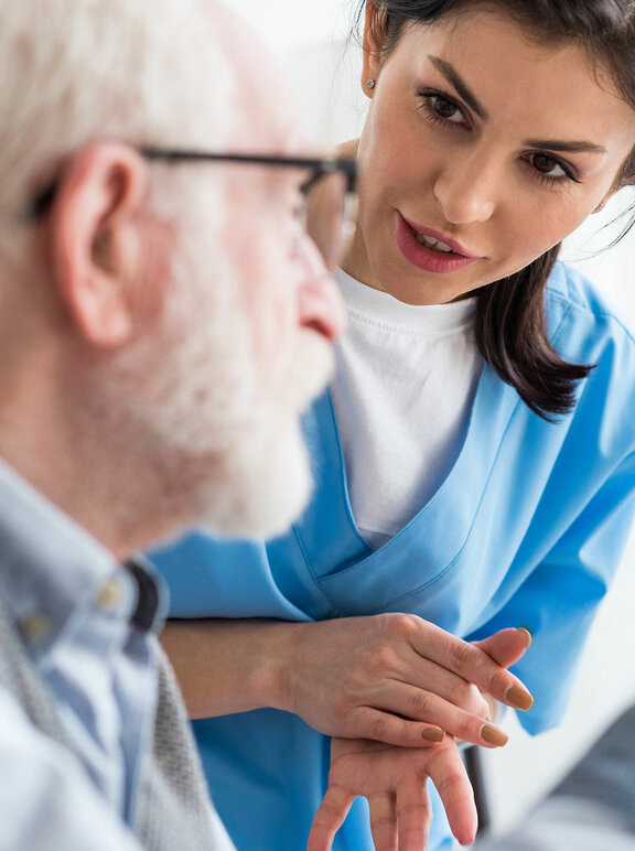 Selektywne skupienie spokojnej pielęgniarki rozmawiającej ze starszym pacjentem