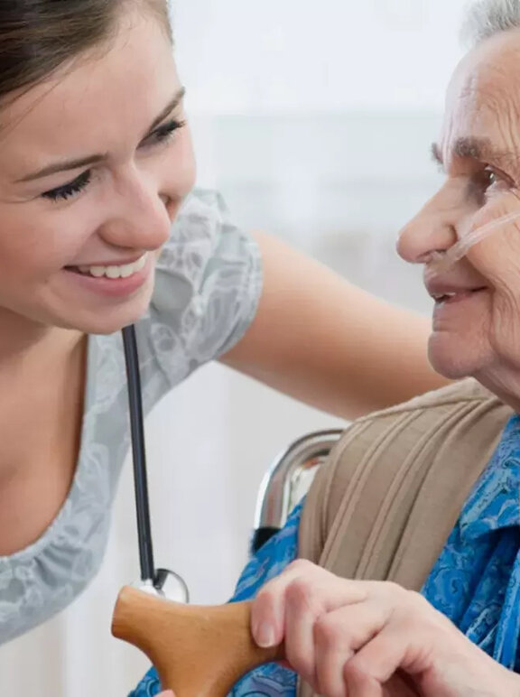 Pielęgniarka trzyma za rękę starszą kobietę