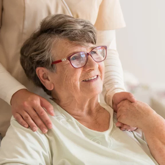 Pielęgniarka z podaje szklankę wody pacjentce w domu
